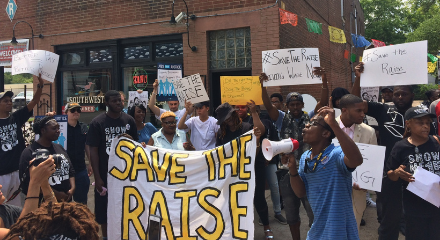St. Louis rally to save the raise with large crowd with signs, banners, and someone speaking in a bullhorn