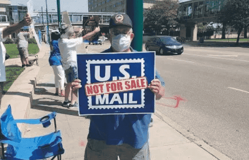 Solidarity with USPS and postal workers - individual holding a sign of US MAIL not for SALE